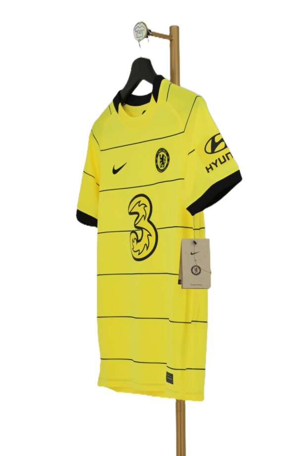 Profil młodzieżowej koszulki wyjazdowej Chelsea FC z widocznym logo Hyundai na rękawie i papierową metką.