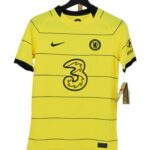 koszulka Chelsea Nike dziecięca z czarnym logo sponsora na wieszaku.