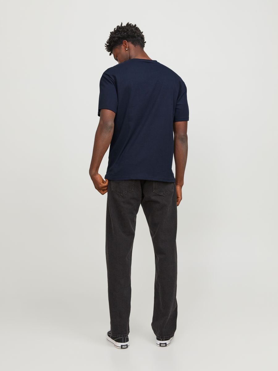 Tył męskiej granatowej koszulki bawełnianej Jack & Jones na modelu z czarnymi jeansami.