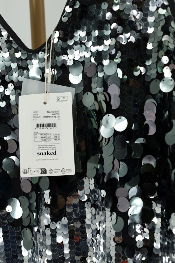 Zbliżenie dekoltu w szpic i papierowej metki Soaked in Luxury z ceną 139 EUR.